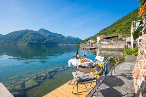 a table and chairs on a dock on a body of water at Casa Tamè - Happy Rentals in Melide