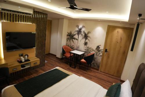 a hotel room with a bed and a television and a table at Trevon Twin Tree Inn in Dhanbād