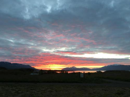 a sunset over a body of water with mountains at Aurora Vacation Homes Fagravik in Akureyri