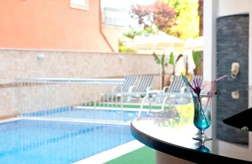 a pool with a table and a vase with flowers on it at Belle Ocean Apart Otel in Alanya