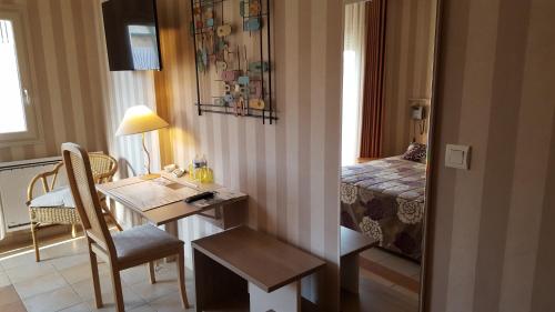 a room with a table and a bedroom with a bed at L'Amphitryon in Coudray