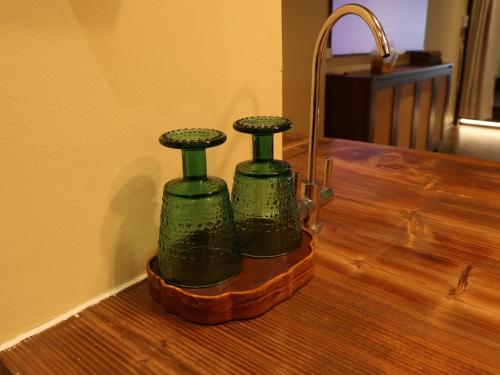 two green glass bottles sitting on top of a wooden table at Smile Home in Hanoi