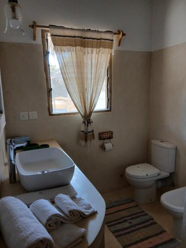 a bathroom with a sink and a toilet and a window at Shira house in Watamu