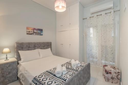 a white bedroom with a bed and a window at Comfy Apt next to metro in Athens