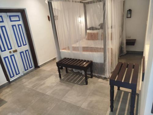 a room with a bed and a bench and a door at The Residence Bentota in Bentota