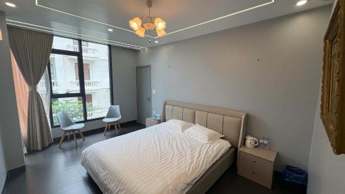 a bedroom with a bed and two chairs and a window at Nâu Homestay in Hai Phong