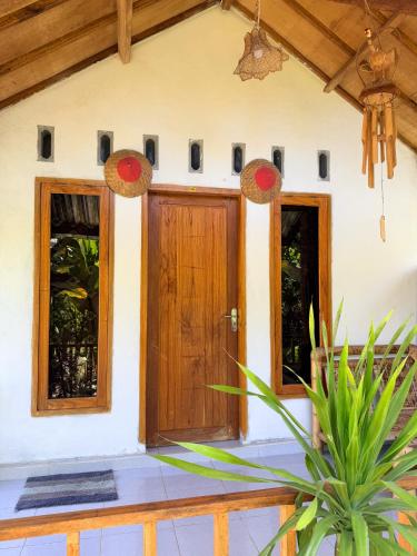 a house with a wooden door and a potted plant at Bintang Homestay in Tetebatu