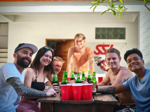 a group of people standing around a table with bottles of beer at Gili Pirates Dive & Social Hostel in Gili Trawangan