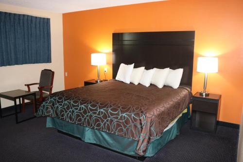Habitación de hotel con 1 cama grande y 2 lámparas en Americas Best Value Inn Giddings, en Giddings