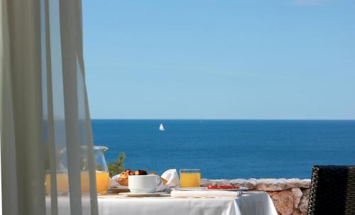a table with food and a view of the ocean at Hotel Monte Turri - Adults Only in Àrbatax