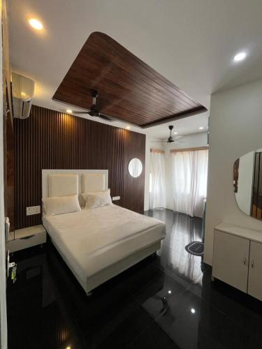 a bedroom with a large white bed and a mirror at Hyton Grand - Kilambakkam in Urapakkam
