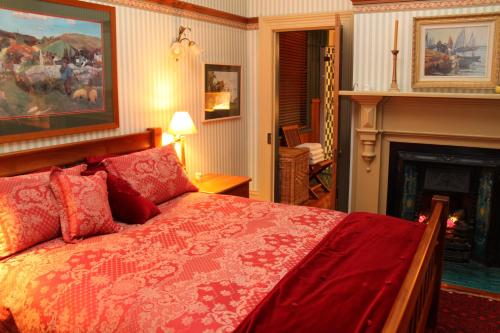 um quarto com uma grande cama vermelha e uma lareira em Villa Rouge B&B em Invercargill