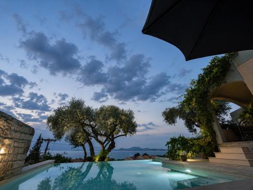 a swimming pool with an umbrella next to a building at Anemos Villa Barbati Corfu in Barbati