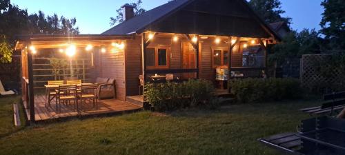a cabin with a deck with a table and lights at Domek Zapach Wyspy in Gdańsk