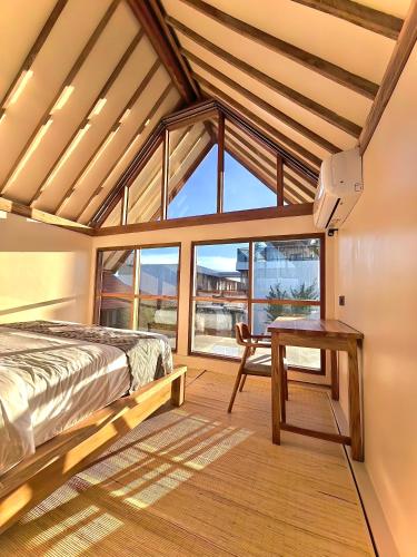 a bedroom with a bed and a table and a window at Kuda Putih Guest House Pandawa in Ungasan