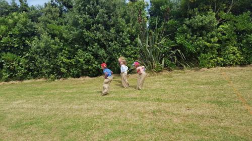 three children are walking in a field at Fitzroy Beach Holiday Park in New Plymouth