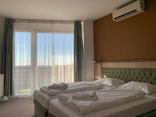 a bedroom with two beds and a large window at Várfal Panzió és Wellness in Pécs
