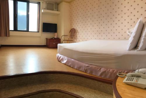 Habitación de hotel con cama y teléfono en Chantai Hotel, en Hualien City