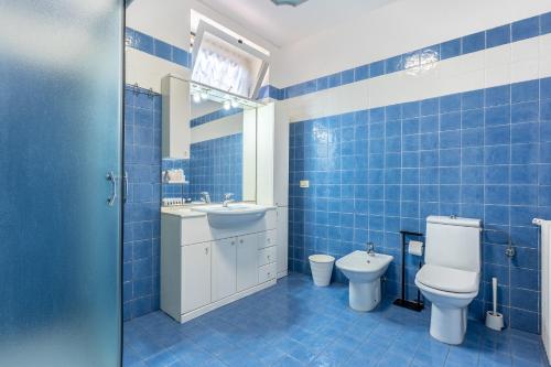 a blue tiled bathroom with a toilet and a sink at Hotel Central Giacomini in Salò