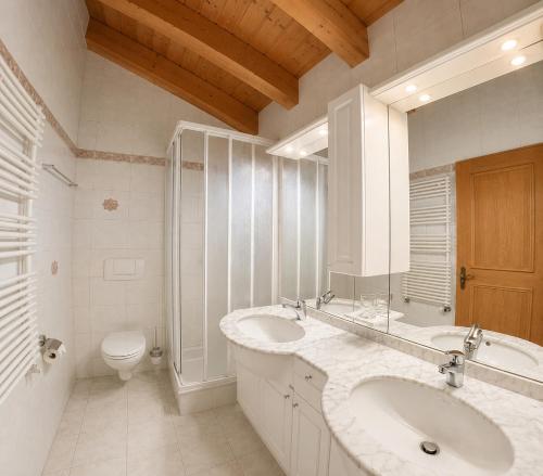 a white bathroom with two sinks and a toilet at Residenz Darianne Leukerbad in Leukerbad