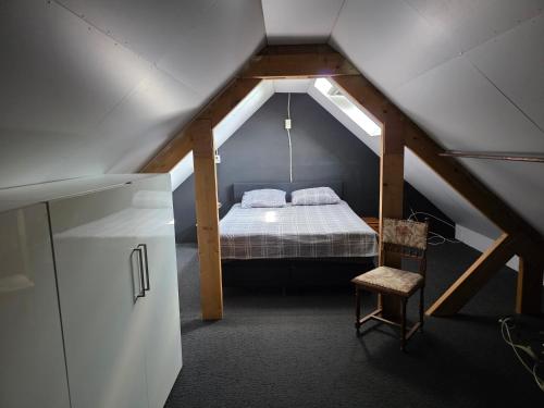 a attic room with a bed and a chair at Kouwenberg in Aarle-Rixtel
