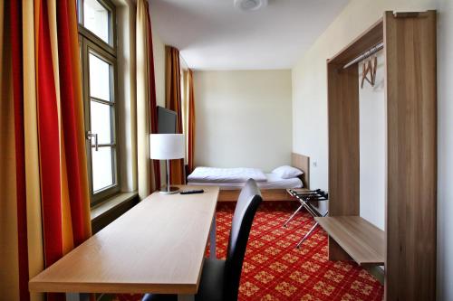 a hotel room with a desk and a bed at Bahnhof Busch in Bretzfeld