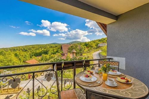 a table on a balcony with a view of the mountains at Vrtin Vineyard Family Retreat - Happy Rentals in Dragatuš
