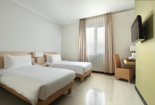 a hotel room with two beds and a television at Hotel Santika Bengkulu in Bengkulu