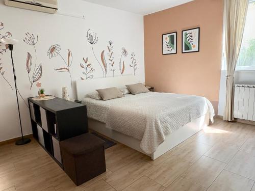 a bedroom with a bed and a lamp and flowers on the wall at Studio Izola in Izola