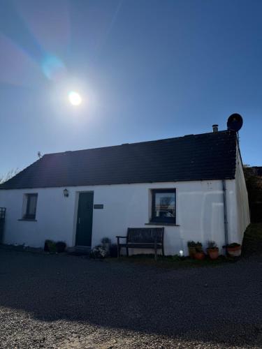a white house with a bench in front of it at Eviedale Cottages ltd in Evie