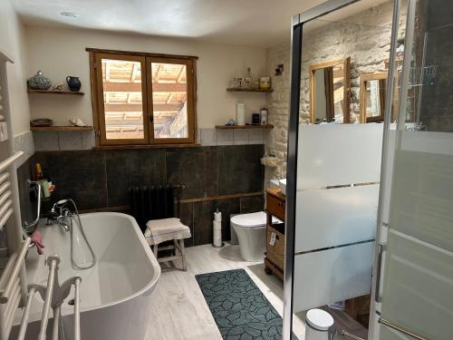 a bathroom with a bath tub and a toilet at Double chambres hôtes parentales in Damvix