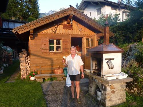 a man standing in front of a wooden house at Appartements Rofangarten in Maurach