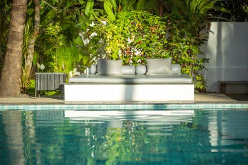 a swimming pool with a bench next to a resort at Pont Bleu Suites - boutique hotel -Riverside & Pool in Canacona