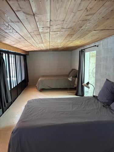 a bedroom with two beds and a wooden ceiling at L Atelier in Angoulême