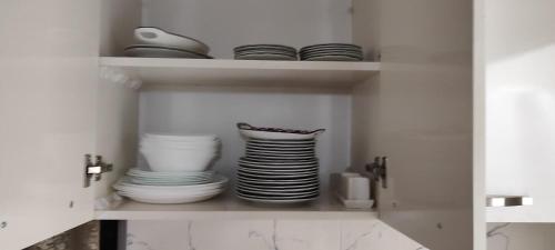 a white cabinet with plates and bowls in it at Nino in Kaspi
