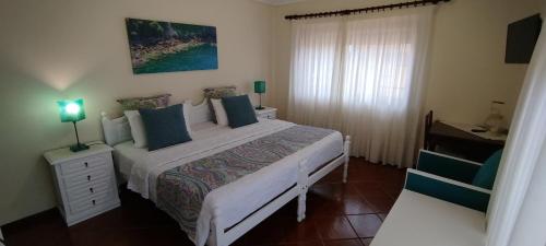 a bedroom with a large white bed with blue pillows at A Casa da Ti Laura - AL in Aveiro