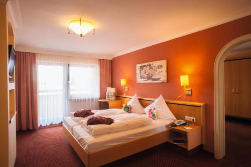 een slaapkamer met een bed met een oranje muur bij Wellness- und Vitalhotel Böhmhof in Bodenmais