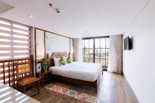 a bedroom with a bed and a large window at Lúa Boutique Hoi An Hotel in Tân Thành (1)