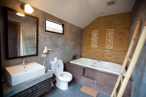 a bathroom with a tub and a toilet and a sink at Chalicha Resort in Chumphon