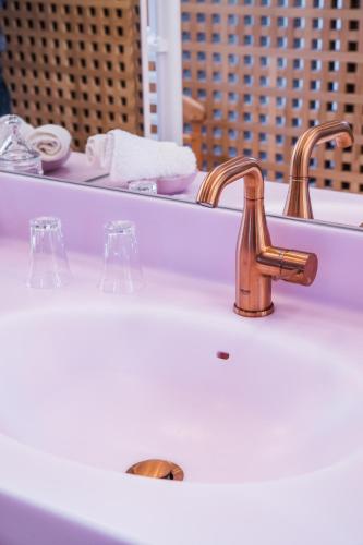 a bathroom sink with a copper faucet and a mirror at Hôtel Restaurant Auprès d'Angèle in Marcillac-Vallon