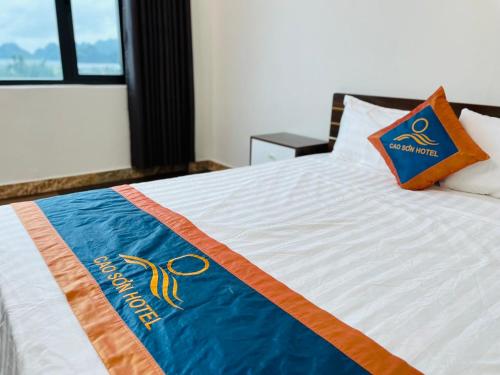 a bed with a blue and orange blanket on it at Khách sạn Cao Sơn in Cửa Ông