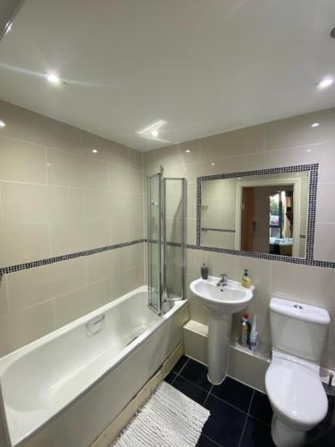 a bathroom with a sink and a toilet and a bath tub at Colindale Central Apartment in Colindale