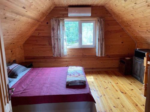 a bedroom in a log cabin with a bed and a window at Затишок in Svityazʼ