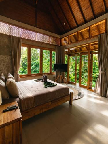 a bedroom with a large bed in a room with windows at LUV-Balian in Balian