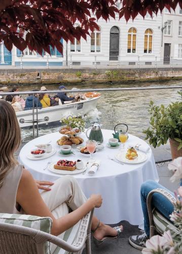 a table with food and people on boats on the water at Hotel Van Cleef in Bruges