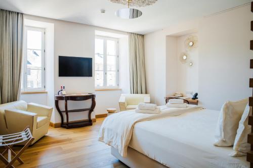 a white bedroom with a bed and a chair and a desk at Hôtel Restaurant Auprès d'Angèle in Marcillac-Vallon