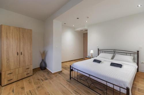 a bedroom with a large bed and a wooden cabinet at arvangroup-apartments in Nafpaktos
