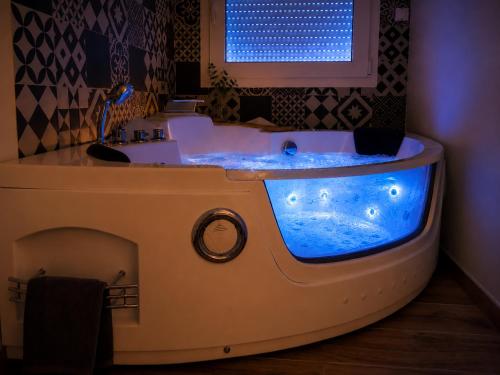 a bath tub with a blue water in it at L'Ardétente - Le Cocon, Piscine et Spa en Ardèche, Adults Only in Lussas