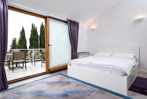 Apartmani Alice في نجيفيش: غرفة نوم بيضاء مع سرير وشرفة