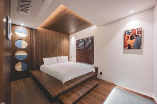 a small bedroom with a white bed and wooden walls at BUSAN Stay 404 in Busan